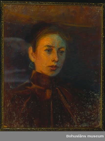 Oljemålning. Kvinna i halvfigur i ett orange ljussken. Kvinnan blickar till höger om konstnären. Hon har på sig en brun sammetsjacka.